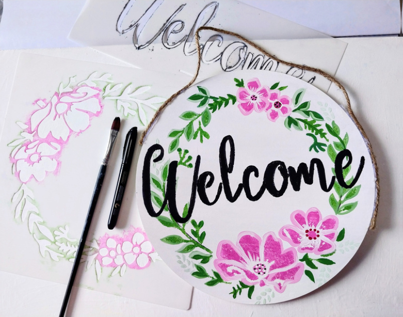 Welcome sign painted on circular wood board