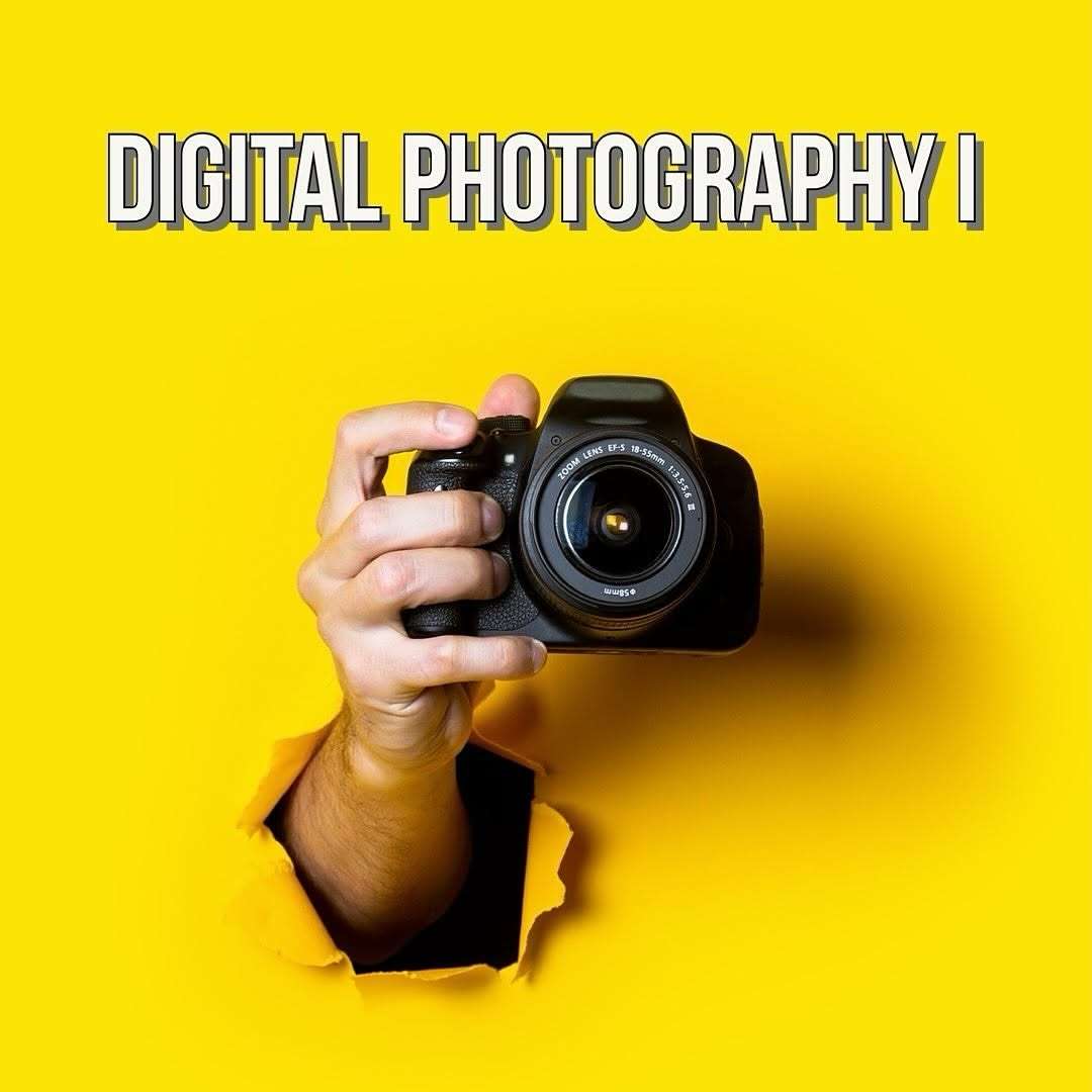 Hand holding a camera, bursting through a yellow background, with the words "Digital Photography I" above it.