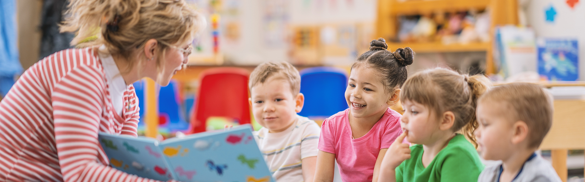 Teacher reading book to preschool children