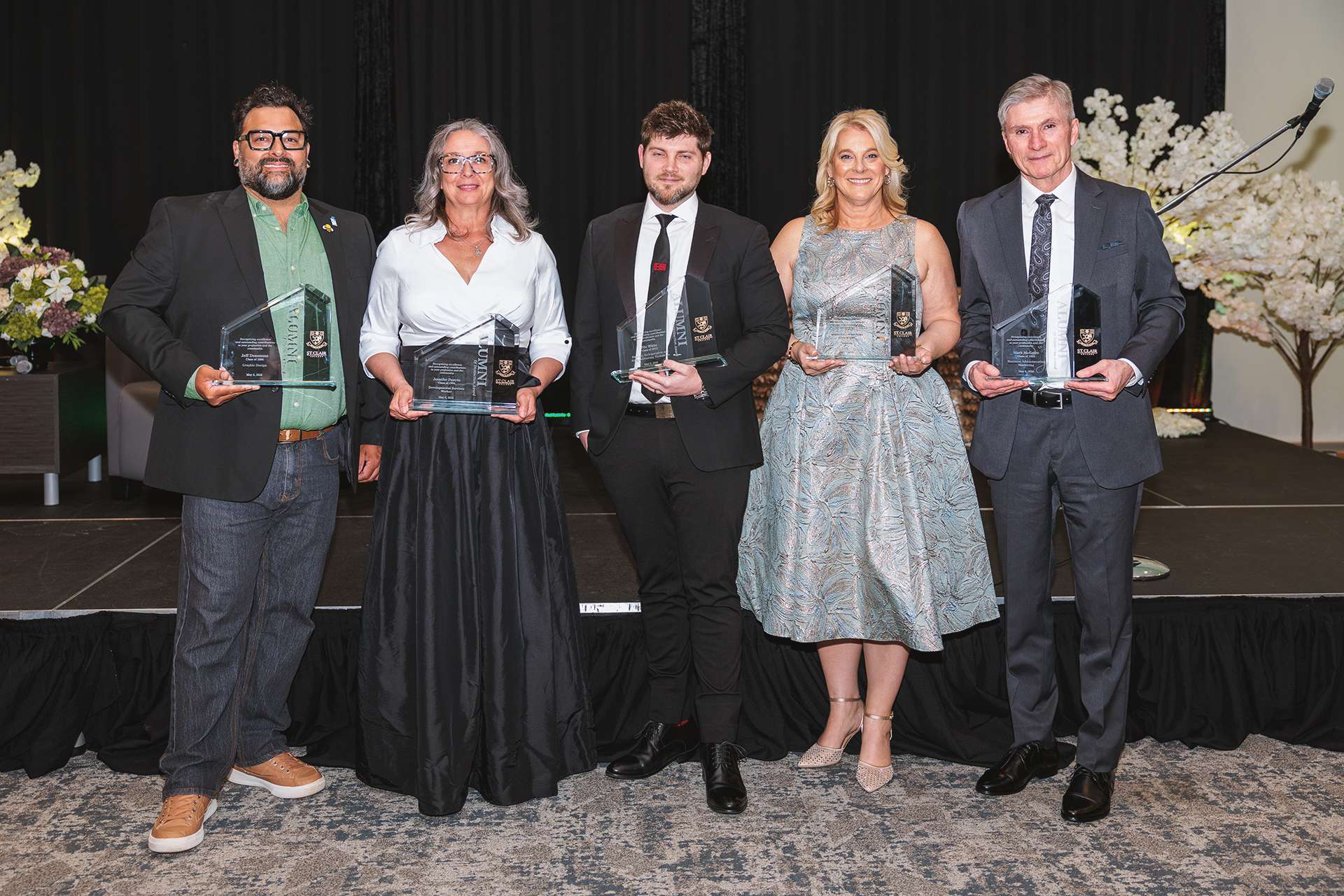 2026 Alumni of Distinction posing with their awards