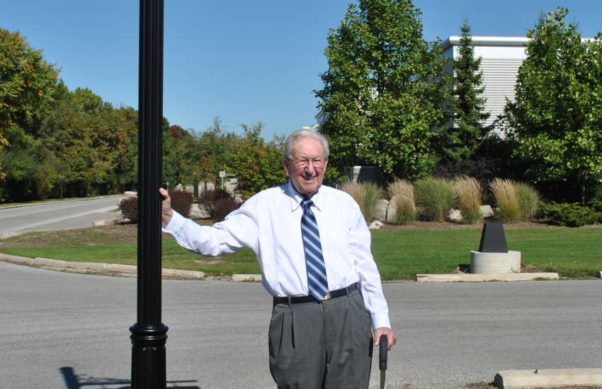 Charles (Charlie) Jackson standing in front of his roadway sign.