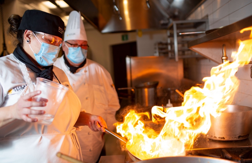 Culinary & Hospitality Management student cooking with fire on the stove.