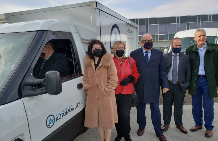 College President Patti France and other officials stand next to an Electric Vehicle prototype.