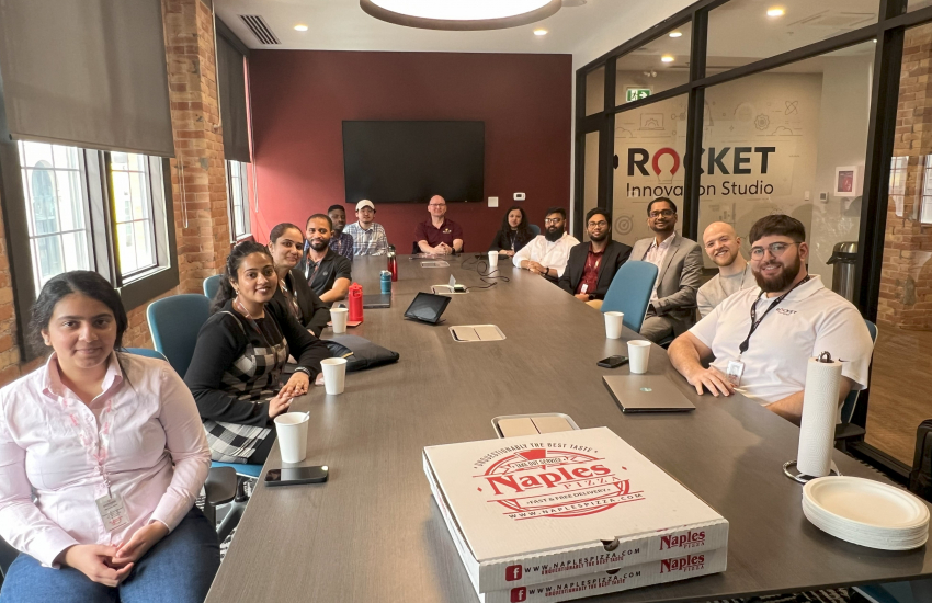 People sitting at conference room table with pizza boxes