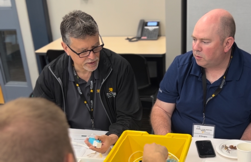 Men at table with bin of parts