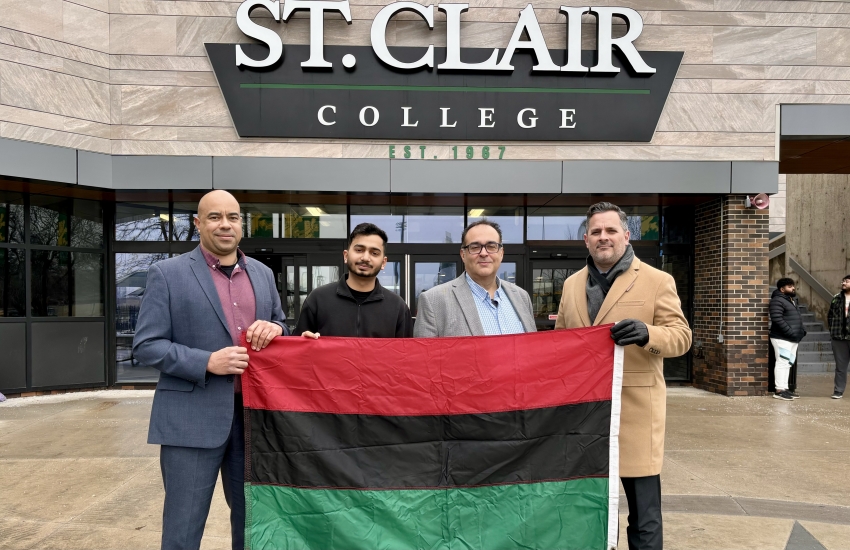 People holding Black History Month flag in front of college