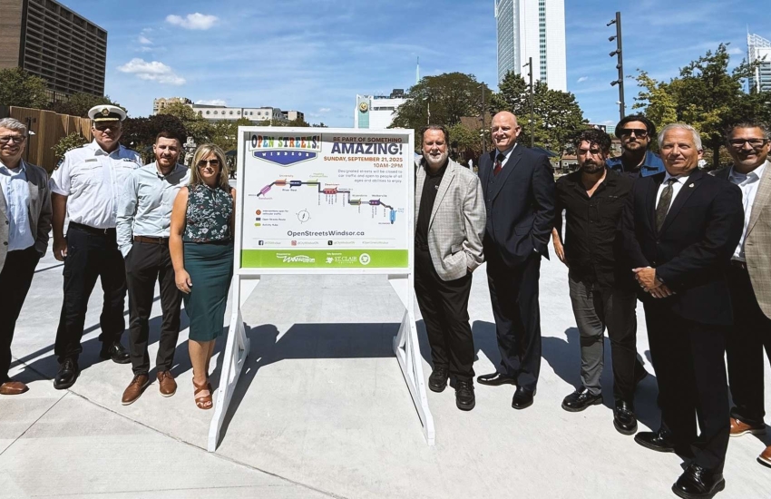 People standing beside Open Streets Windsor sign