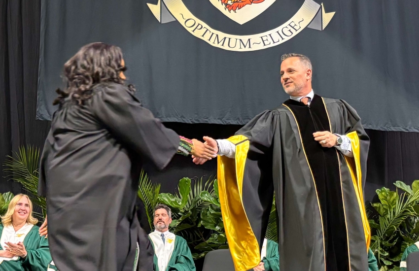 St. Clair College President Michael Silvaggi shakes hands with a student on stage during a Fall 2025 Convocation ceremony.