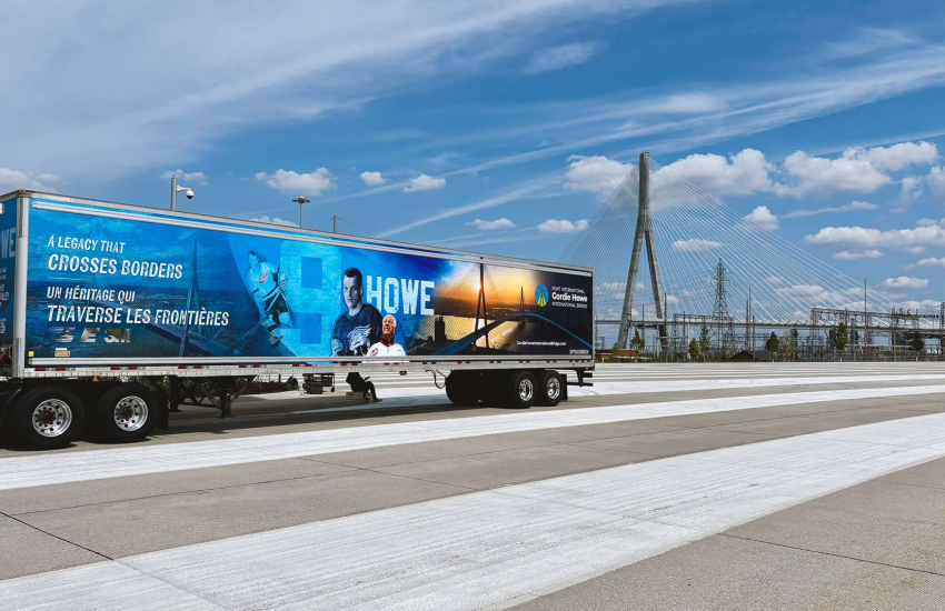 Transport truck driving with bridge in background