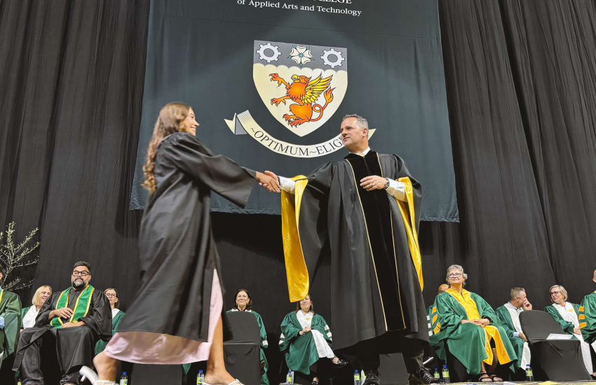 St. Clair College President shakes hands with a graduate as they cross the stage