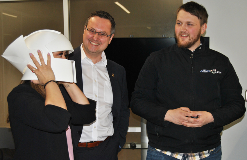 Two men watching woman try on white helmet