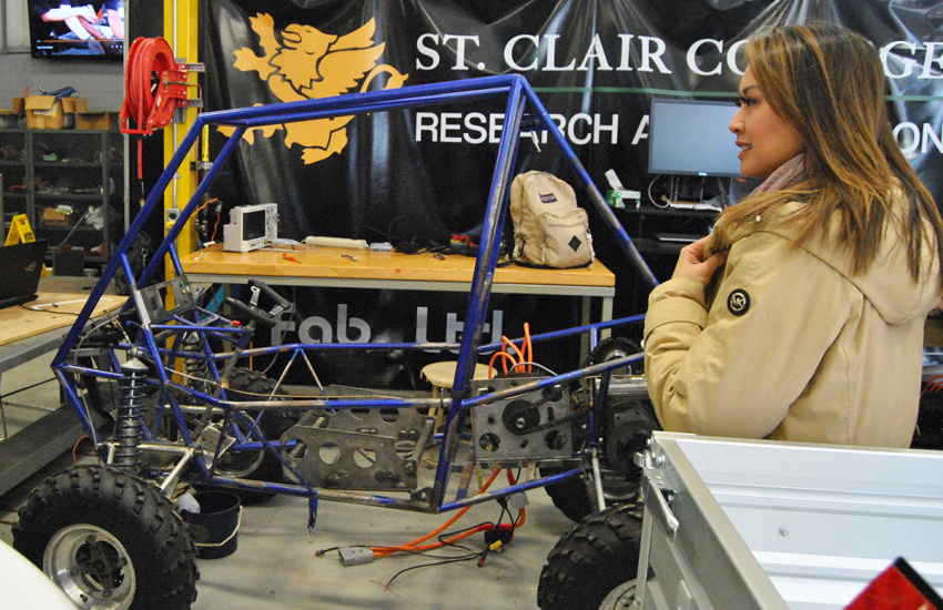 Woman standing next to bare bones frame off road vehicle