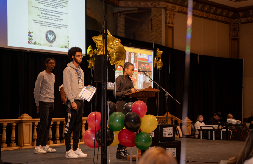 Presenters on stage with balloons in front
