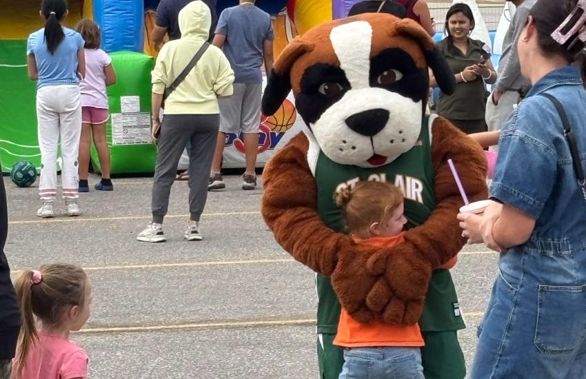 A young child gives Griff a hug at the Alumni Association’s Family Fun Day at Main Windsor Campus on Sept. 13, 2025. 
