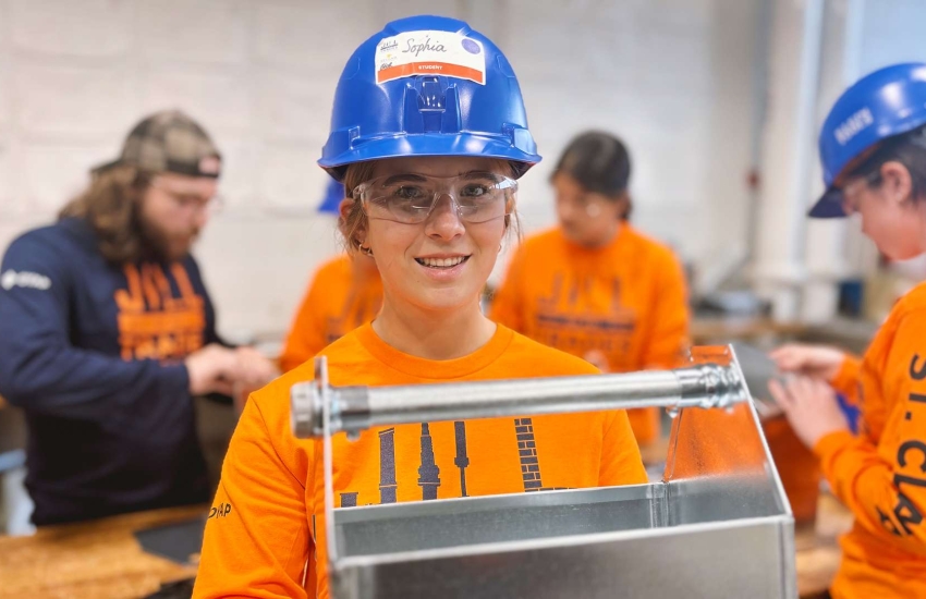 A student holds up a sheet metal toolbox 
