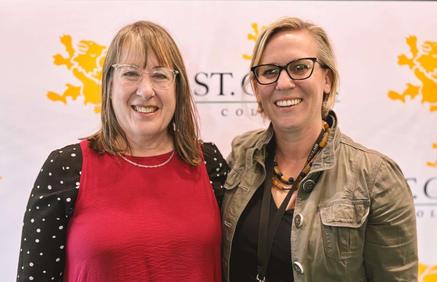 2 women in front of College banner