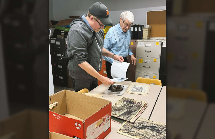 Mike Evans and Bill Totten review photos in the St. Clair College archive room
