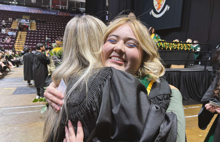 A graduate and faculty member embrace 