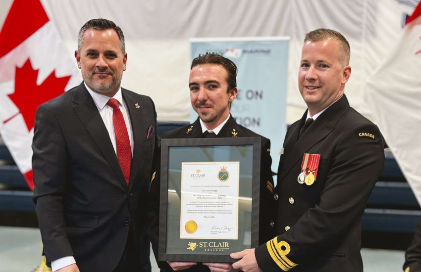 St. Clair College President Michael Silvaggi presents a plaque to Sailor 1st Class Blake Blanchard and HMCS Hunter Lt. Commander Chris Elliott