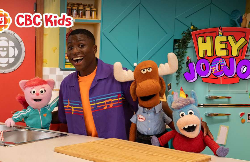 Joojo Paintsil poses with co-host, Gary the Unicorn, and other characters in a promotional graphic for CBC Gem's Hey Joojo!