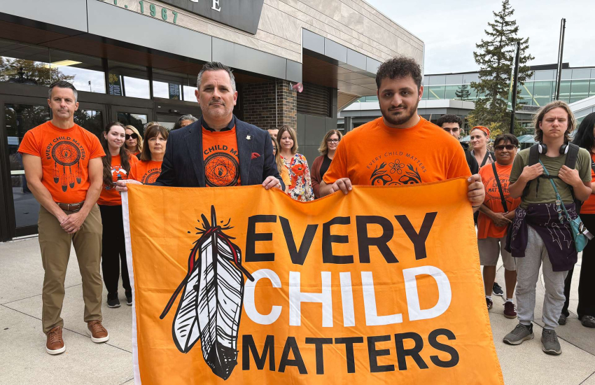 St. Clair College President Michael Silvaggi and SRC President Ali Hadwan hold the Every Child Matters flag