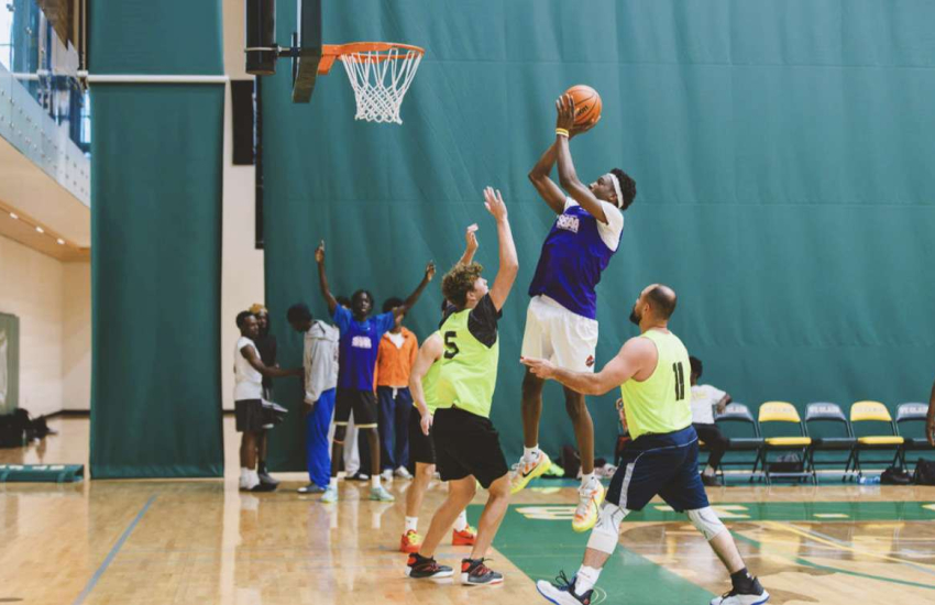 Man jumping above defenders for close to rim shot