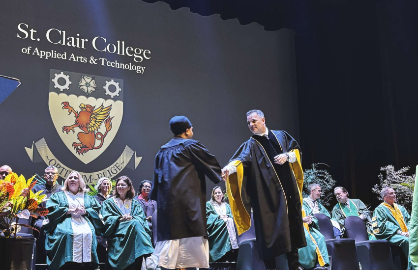 St. Clair College President Michael Silvaggi shakes hands with a student as she crosses the stage at Winter Convocation to receive her stole and diploma