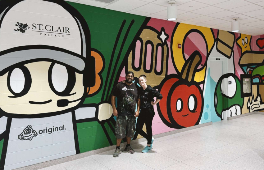 Man and woman standing in front of colorful mural