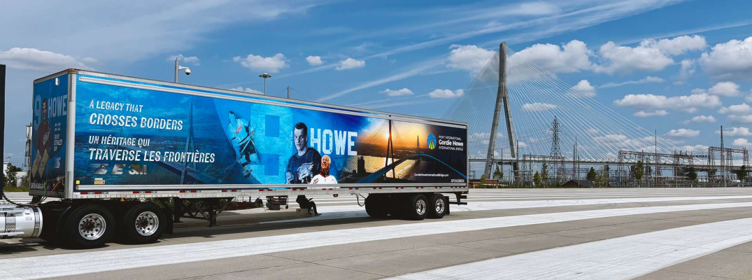 Transport truck driving with bridge in background
