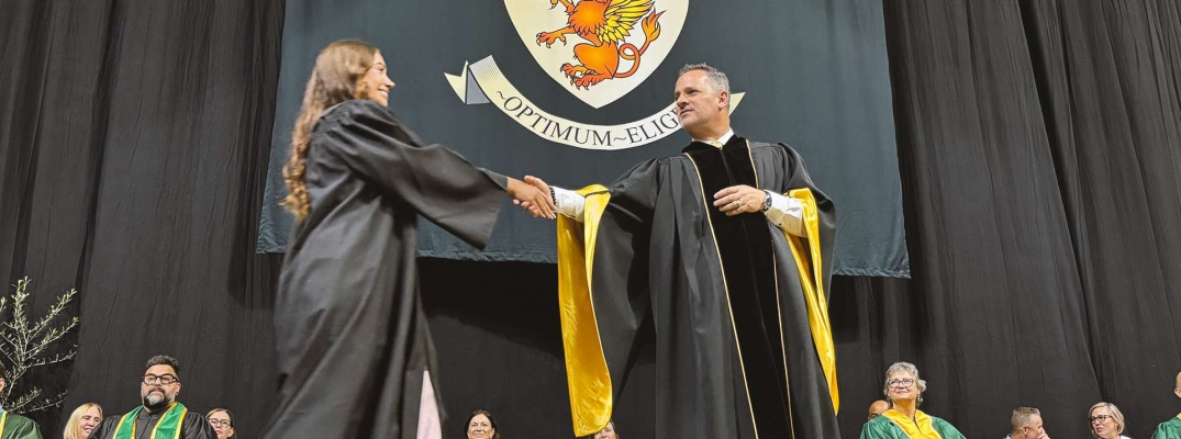 St. Clair College President shakes hands with a graduate as they cross the stage