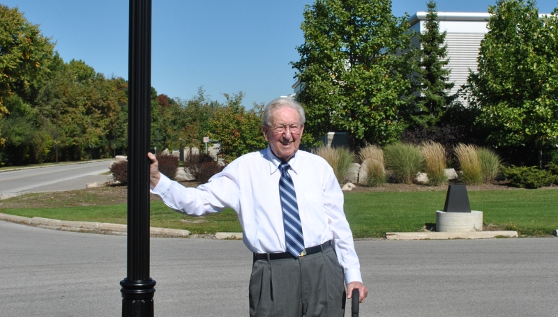Charles (Charlie) Jackson standing in front of his roadway sign.