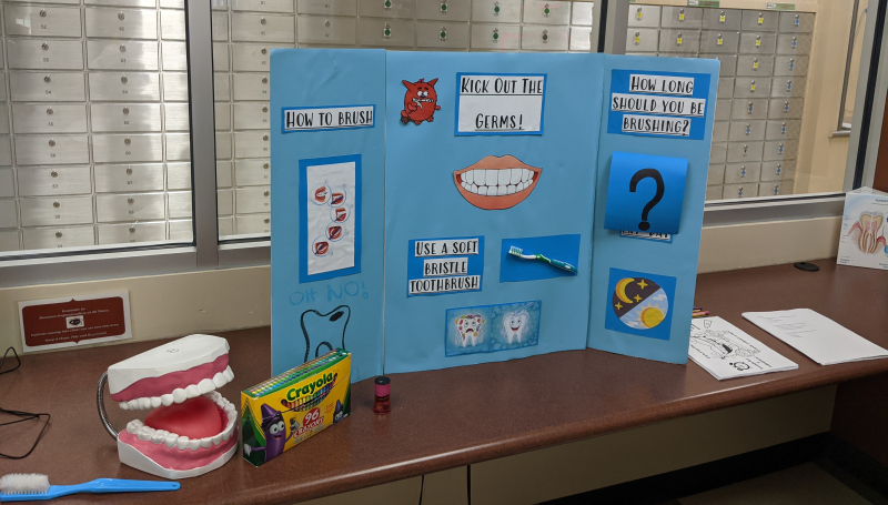 Kick Out the Germs poster on desk with mouth prop