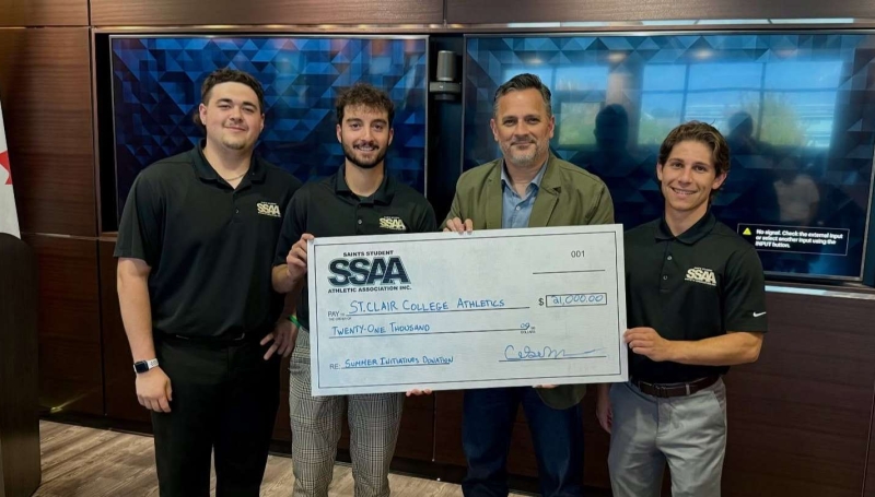 SSAA Board members Andrew Weiler, George Karatzias and Matteo Palumbo stand with St. Clair College President Michael Silvaggi to deliver a cheque for $21,000 to Saints Athletics on Sept. 19, 2025.