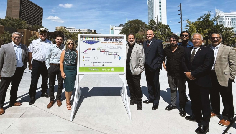 People standing beside Open Streets Windsor sign