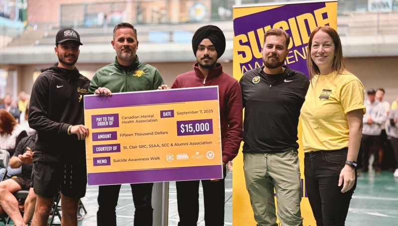 St. Clair College President Michael Silvaggi and student government leaders stand with Nicole Sbrocca of the CHMA to present a cheque