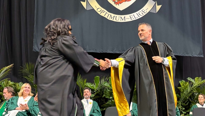 St. Clair College President Michael Silvaggi shakes hands with a student on stage during a Fall 2025 Convocation ceremony.