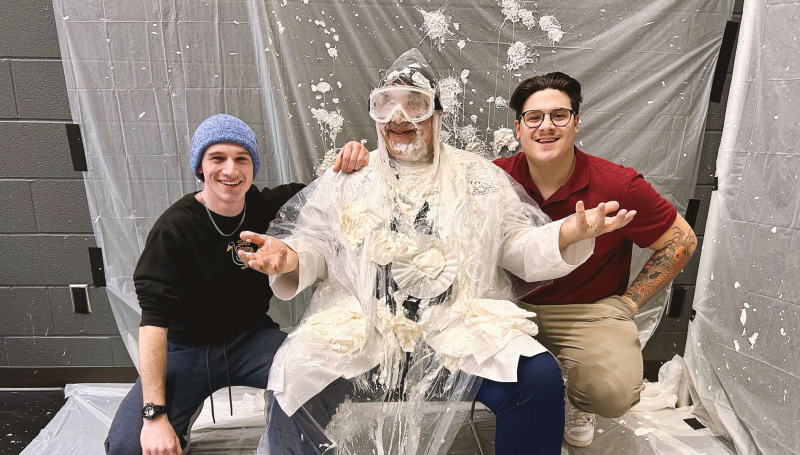 John Lassaline poses with two students who covered him with whipped cream during the Pie Your Prof
