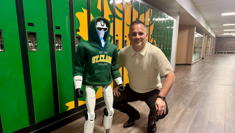St. Clair College President Michael Silvaggi poses with the college’s new R1 humanoid robot at Main Windsor Campus on July 20, 2026.