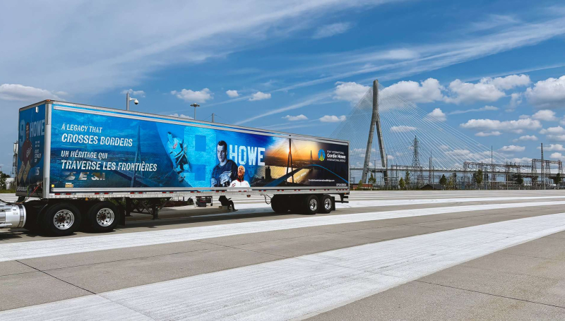 Transport truck driving with bridge in background