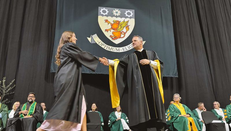St. Clair College President shakes hands with a graduate as they cross the stage