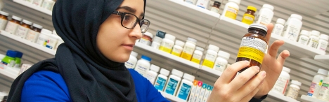 Pharmacy technician student looking at bottle of pills
