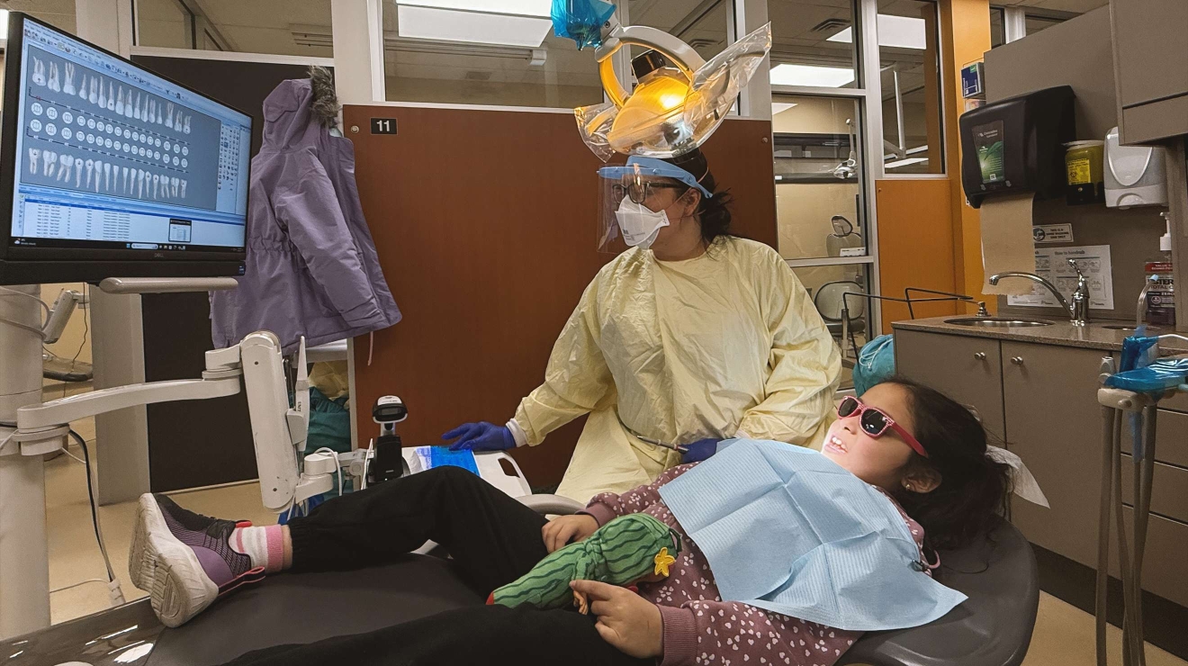 Hygienist working with a young patient sitting in a dental chair