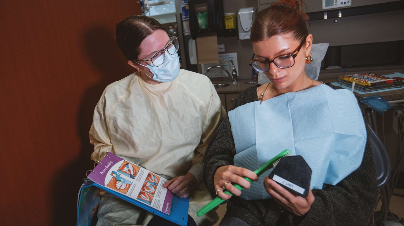 Hygienist showing patient how to properly brush teeth